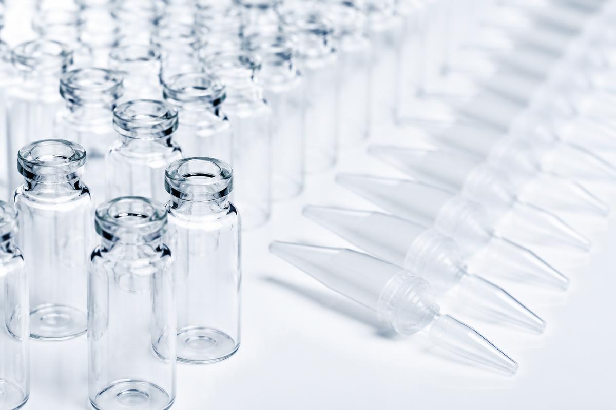 Viales de laboratorio transparentes y puntas de pipeta sobre una superficie blanca